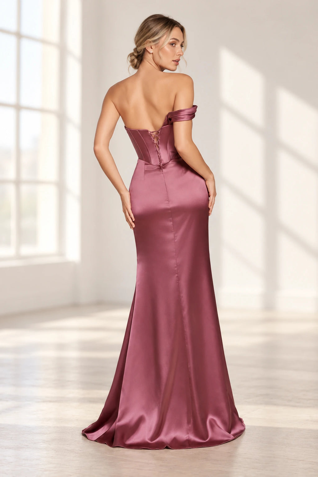 Back view of a mauve rose fitted prom dress with a low lace-up corset back, single draped sleeve, and gently flared floor-length skirt.
