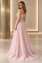Back view of blush pink beaded tulle prom dress featuring strapless ruffle trim, center back closure, satin waistband and flowing embellished A-line skirt