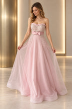Blush pink beaded tulle A-line prom dress with strapless sweetheart neckline, sparkling embellished bodice, satin bow waist and flowing floor length skirt by Graceprom