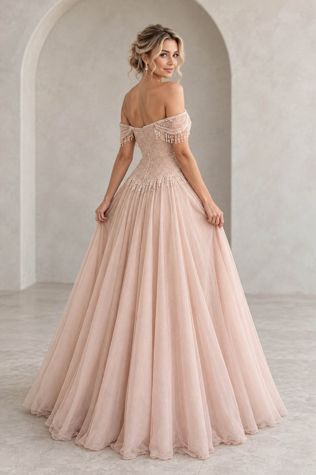 Back view of Graceprom blush tulle prom dress with a low zipper back, beaded fitted bodice, fringe details and flowing A-line skirt.