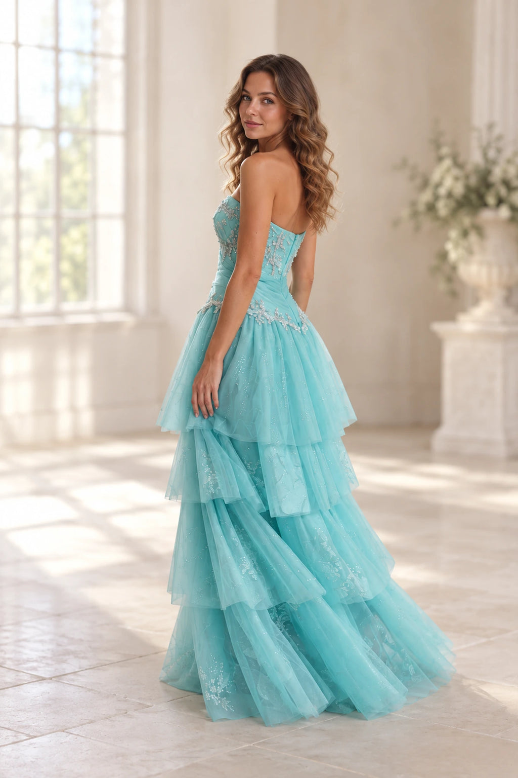 Side back view of aqua blue tulle prom dress featuring strapless fitted bodice, floral beadwork, ruched waist and cascading tiered ruffle skirt