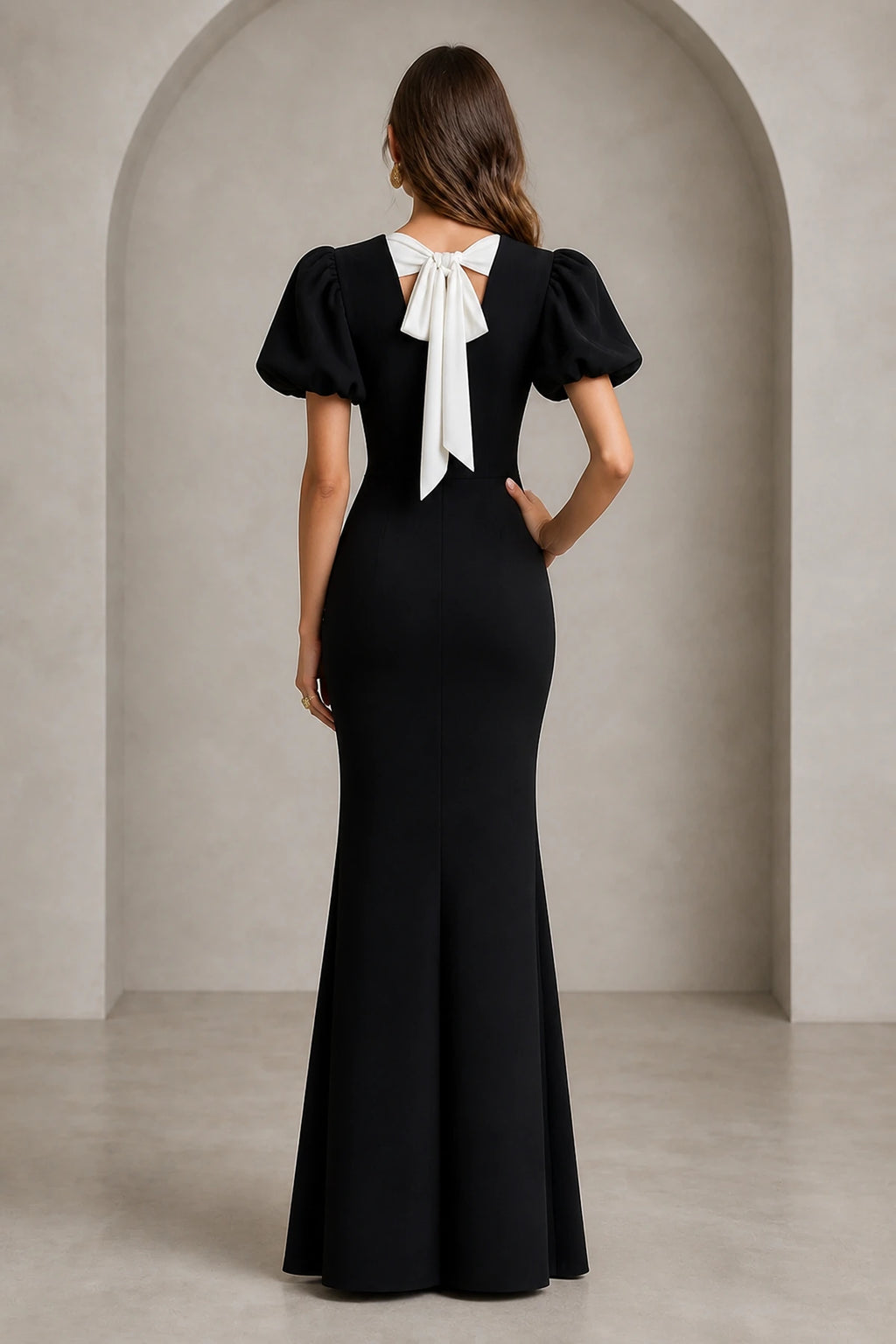 Back view of black mermaid evening dress with short puff sleeves and white statement bow