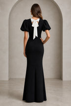 Back view of black mermaid evening dress with short puff sleeves and white statement bow