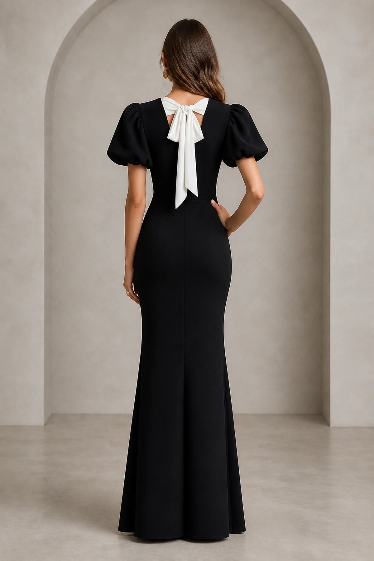 Back view of black mermaid evening dress with short puff sleeves and white statement bow