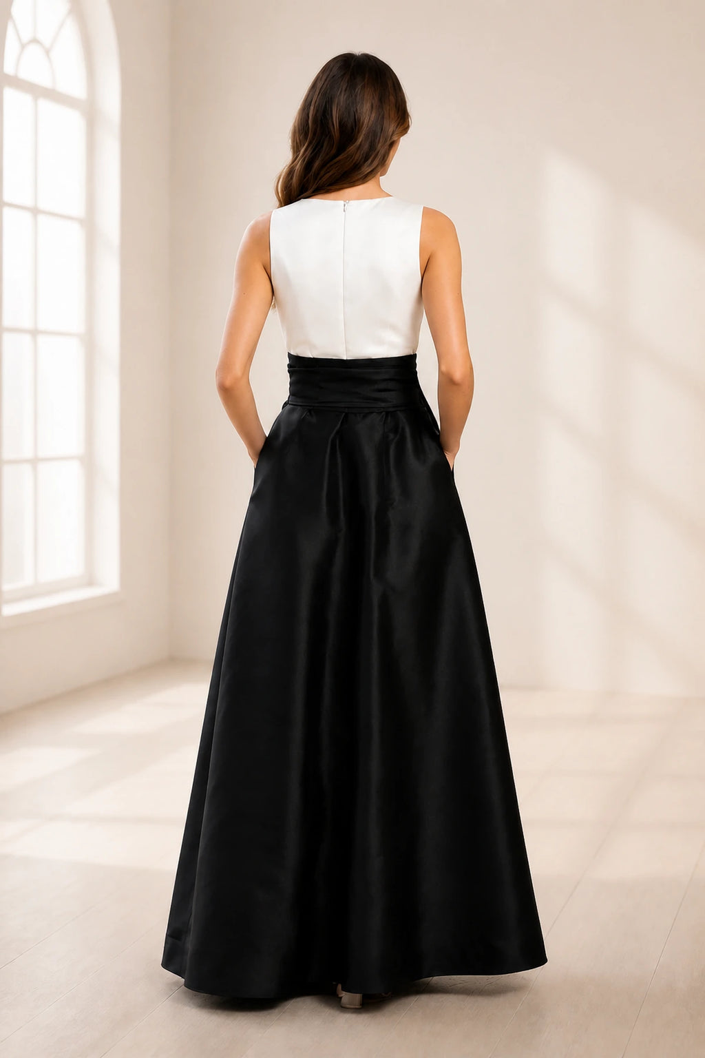 Back view of black and white wedding guest dress with sleeveless white bodice, center zipper and full black floor-length skirt