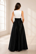 Back view of black and white wedding guest dress with sleeveless white bodice, center zipper and full black floor-length skirt