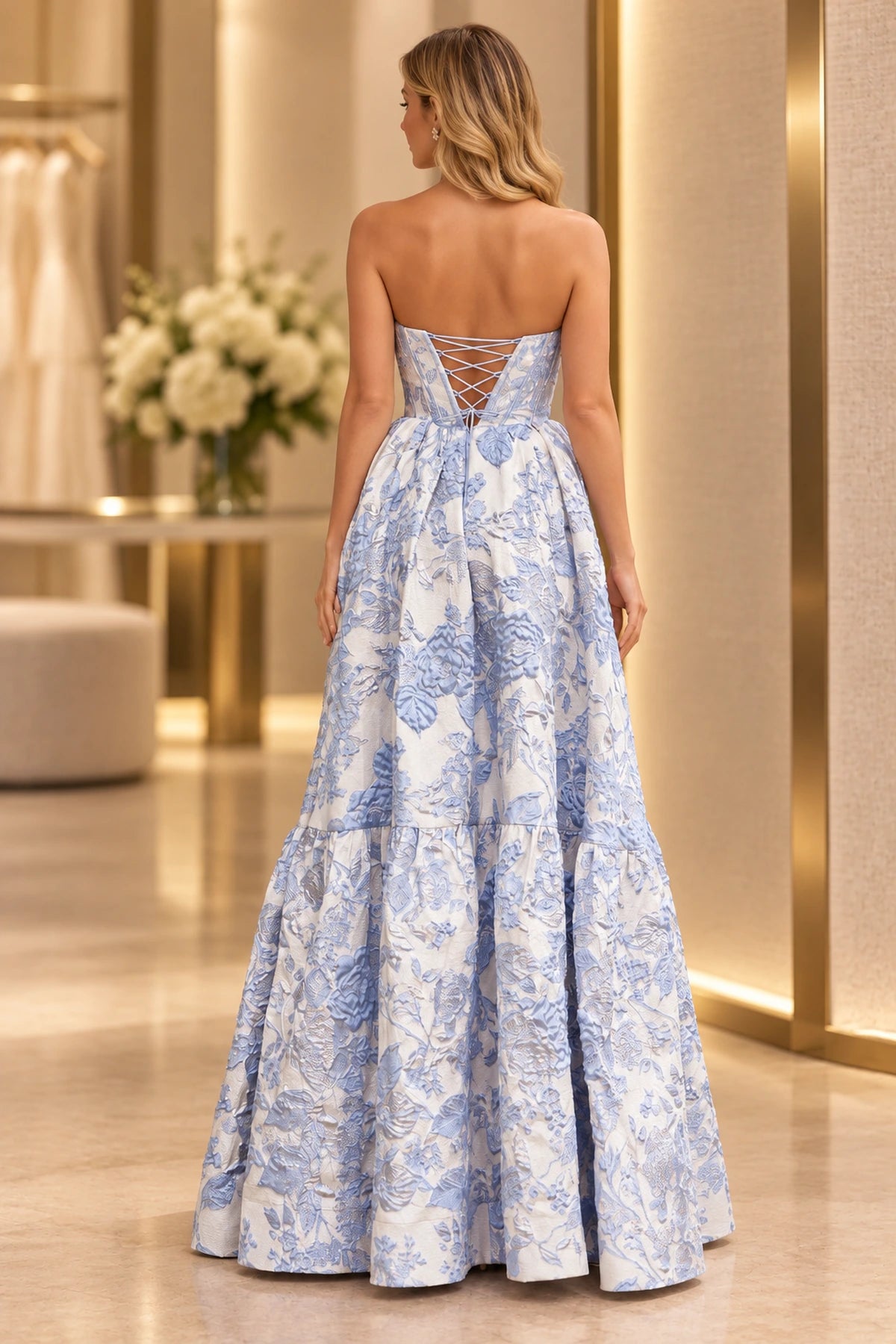 Back view of blue and ivory floral prom dress featuring a lace-up corset back, fitted waist and voluminous floor-length tiered A-line skirt.