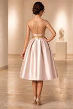 Back view of GraceProm blush pink midi wedding guest dress with sheer embellished top and zipper closure
