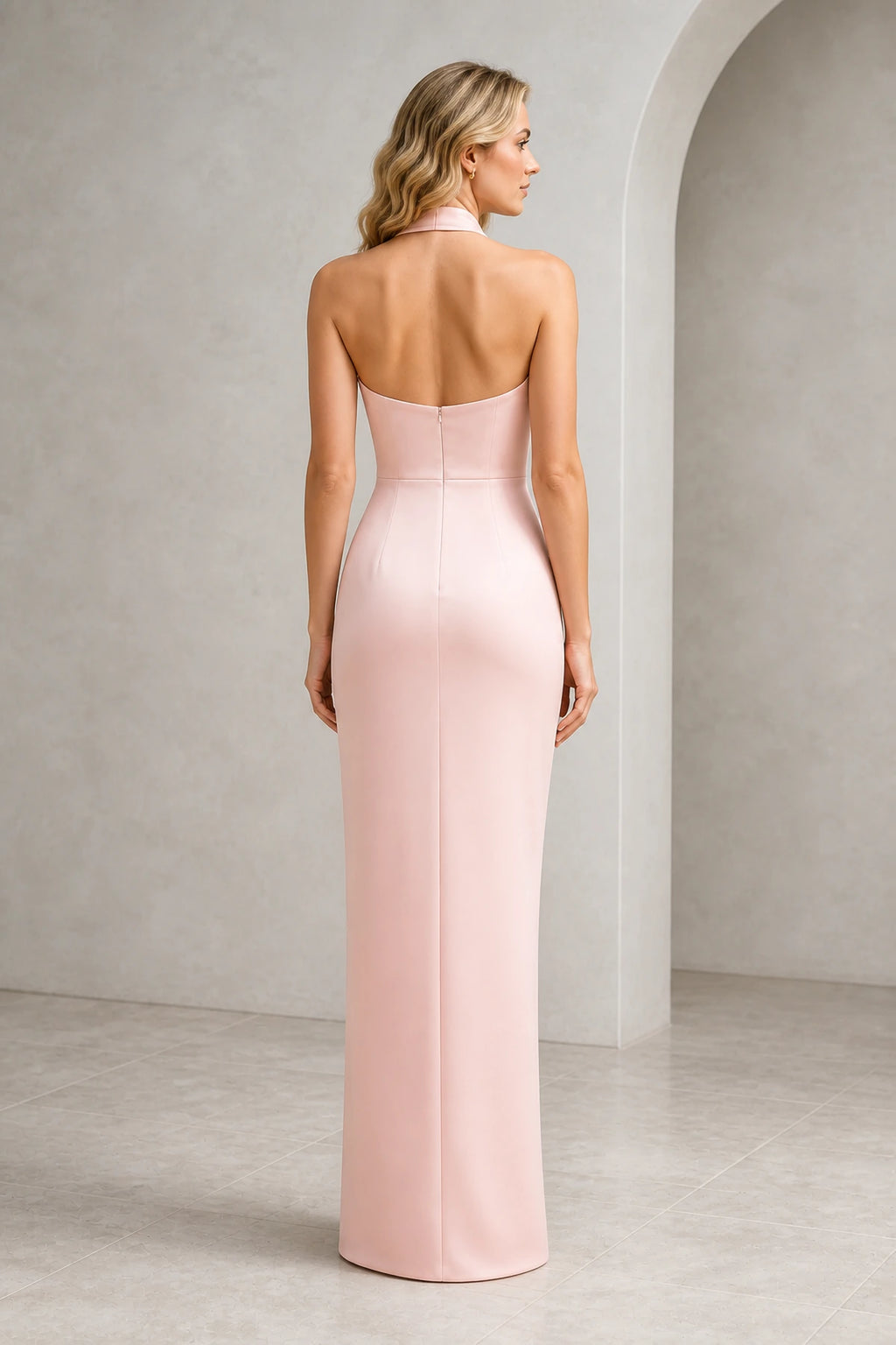 Back view of blush pink wedding guest dress with halter neckline, open back, center zipper and floor-length sheath silhouette