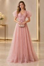 Blush pink A line prom dress with a V neckline, sheer puff sleeves, small front bows, ruched waistband, and sparkling floor-length skirt.