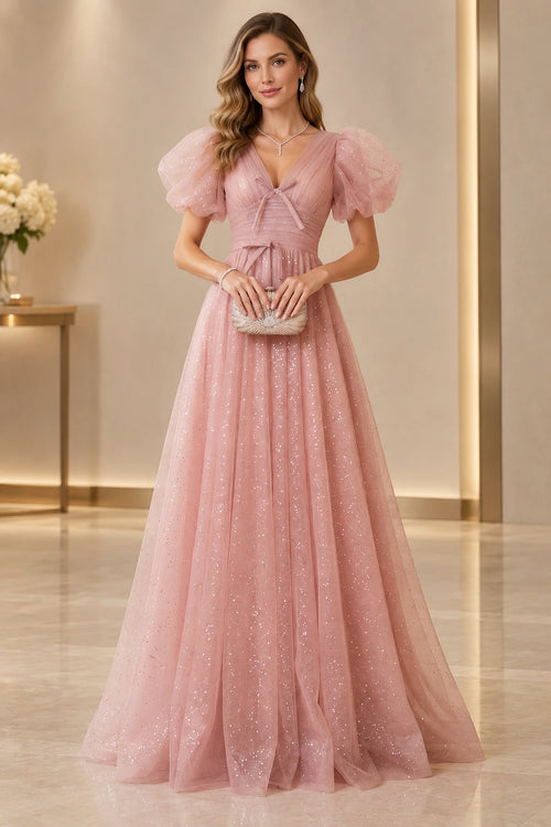 Blush pink A line prom dress with a V neckline, sheer puff sleeves, small front bows, ruched waistband, and sparkling floor-length skirt.