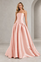 Blush pink strapless A line prom dress with a straight neckline, elongated fitted bodice, curved drop waist, and full gathered floor-length skirt.