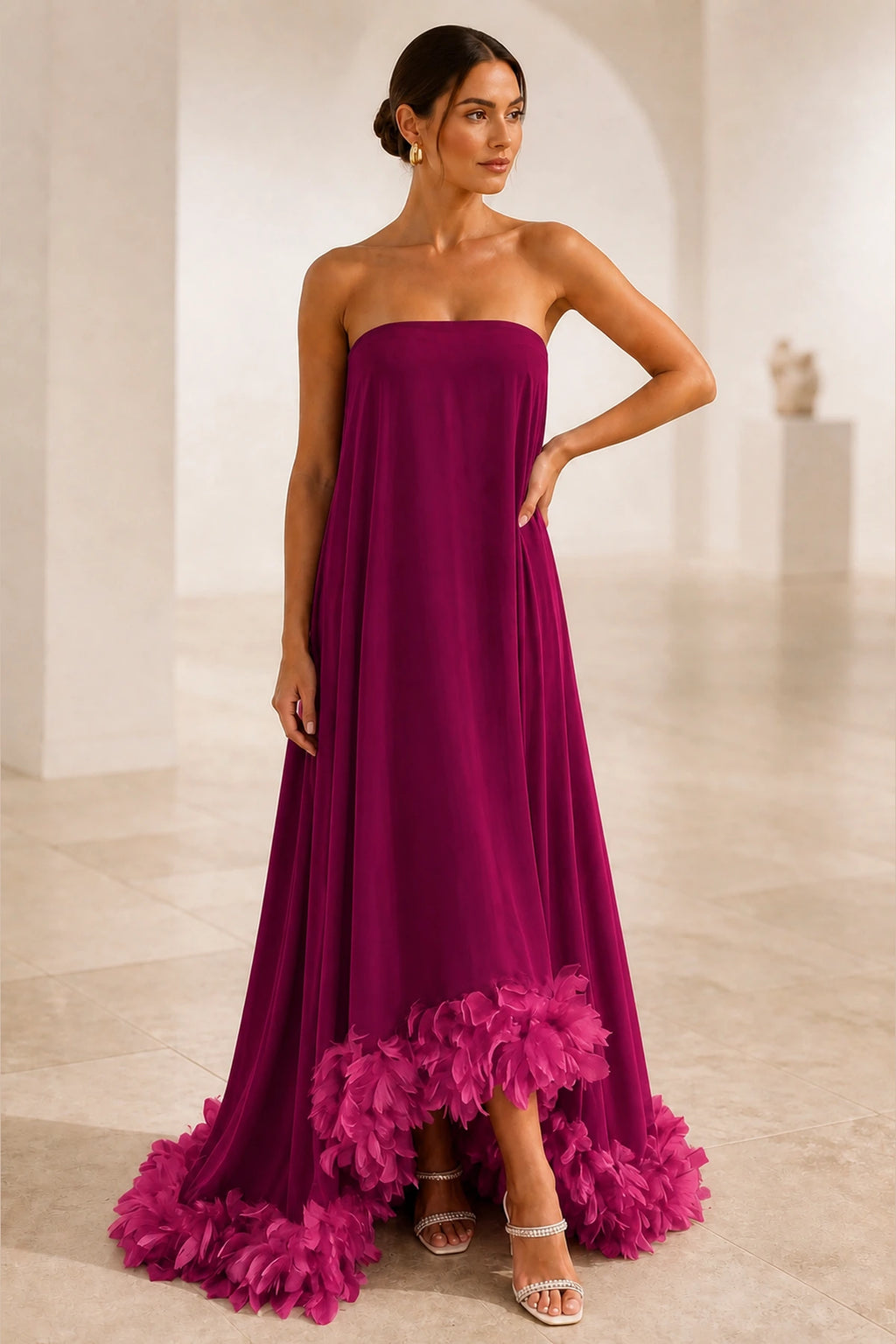 Burgundy strapless A-line wedding guest dress with straight neckline, flowing skirt and fuchsia feather-style hem