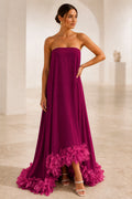 Burgundy strapless A-line wedding guest dress with straight neckline, flowing skirt and fuchsia feather-style hem