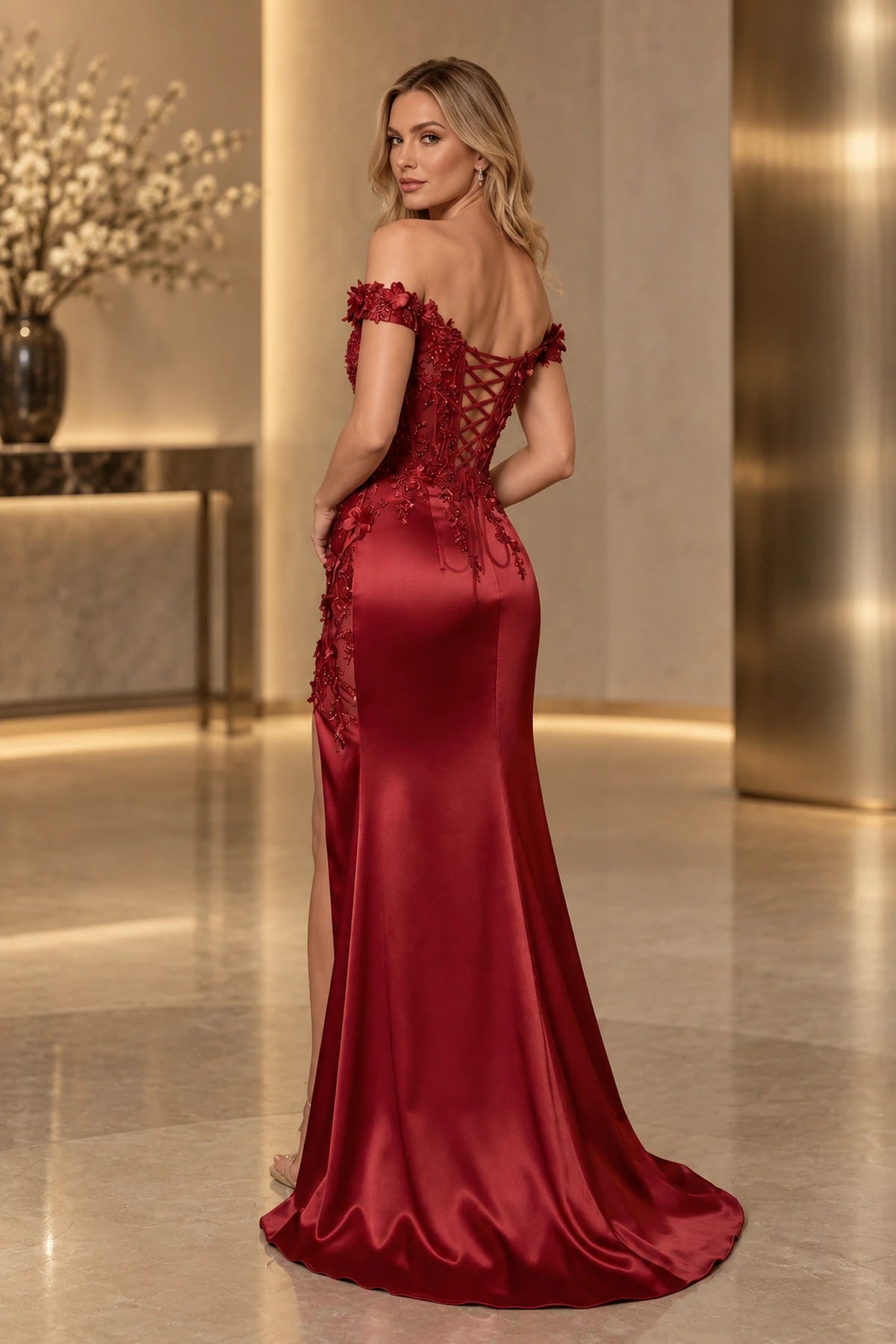 Back view of burgundy mermaid prom dress featuring floral cap sleeves, crisscross lace-up corset back, floral appliques, fitted satin-look skirt, and sweeping hem.