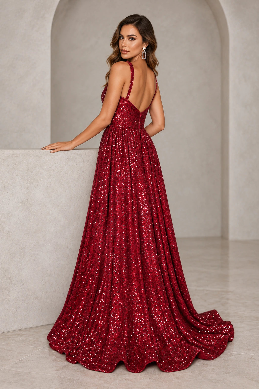 Burgundy sequined prom dress featuring a low V back, center-back zipper, gathered A line skirt, and gentle train.