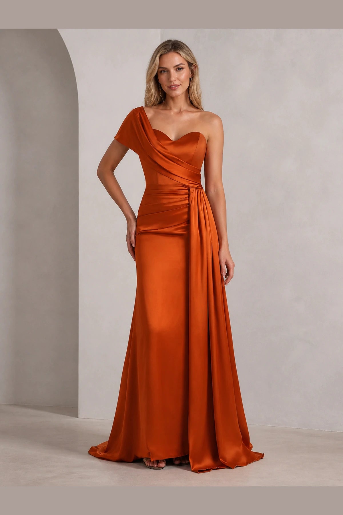 Front view of Vedress burnt orange wedding guest dress with sweetheart neckline, one shoulder drape, ruched waist and floor length skirt