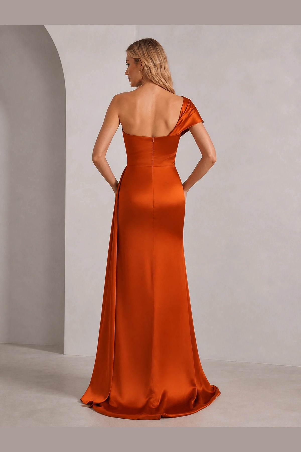 Back view of Vedress burnt orange wedding guest dress with asymmetric open back, one shoulder design, center zipper and long silhouette