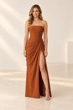 Burnt orange strapless bridesmaid dress with a straight neckline, ruched waist, floor-length skirt, and high front slit.