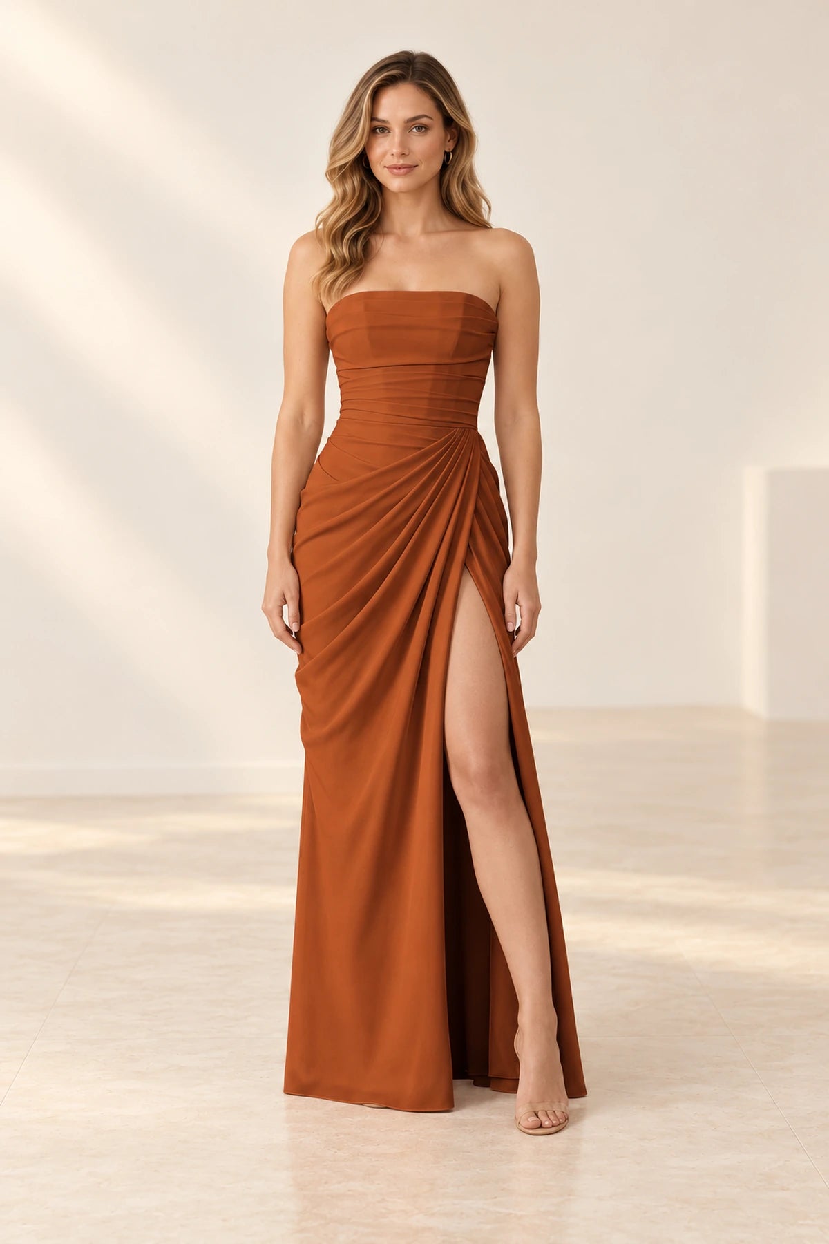 Burnt orange strapless bridesmaid dress with a straight neckline, ruched waist, floor-length skirt, and high front slit.