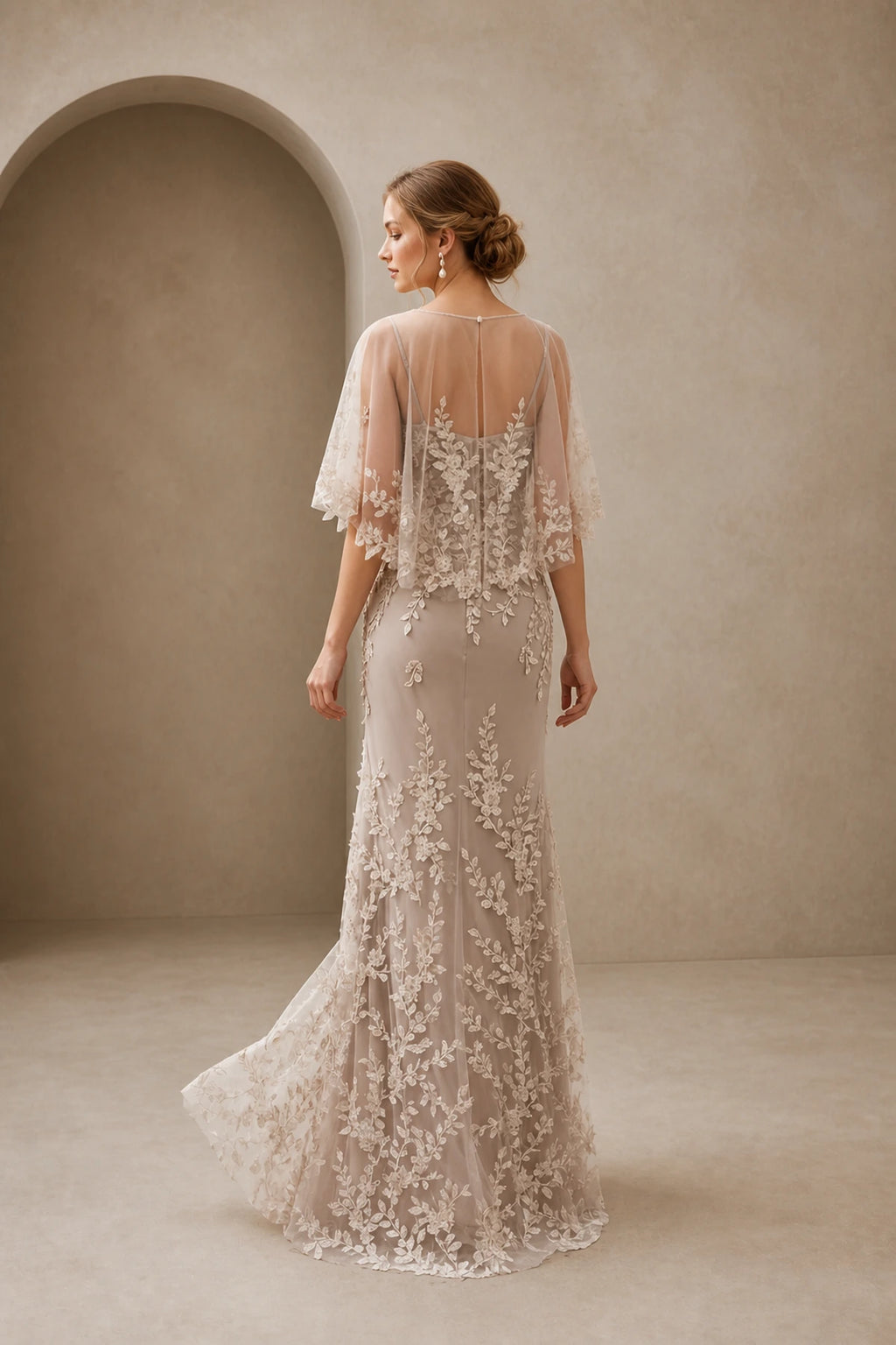 Back view of champagne lace mother of the bride dress with sheer keyhole back, cape sleeves and floor-length skirt