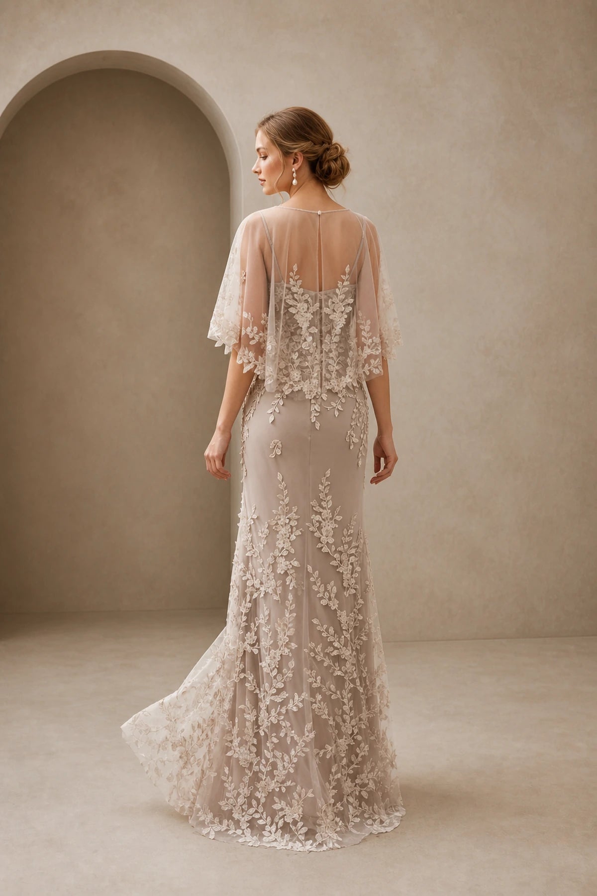 Back view of champagne lace mother of the bride dress with sheer keyhole back, cape sleeves and floor-length skirt
