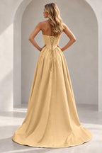 Champagne prom dress showing a paneled lace-up back with matching backing panel, long waist ties, full gathered skirt, and train.