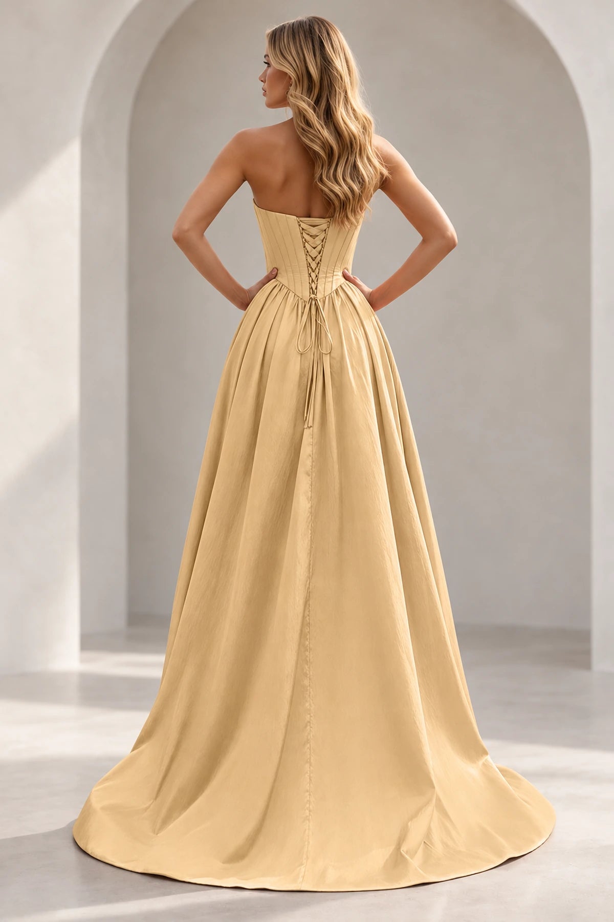 Champagne prom dress showing a paneled lace-up back with matching backing panel, long waist ties, full gathered skirt, and train.