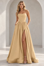 Champagne strapless A line prom dress with a pleated foldover neckline, pointed corset-style waist, gathered skirt, and thigh-high slit.
