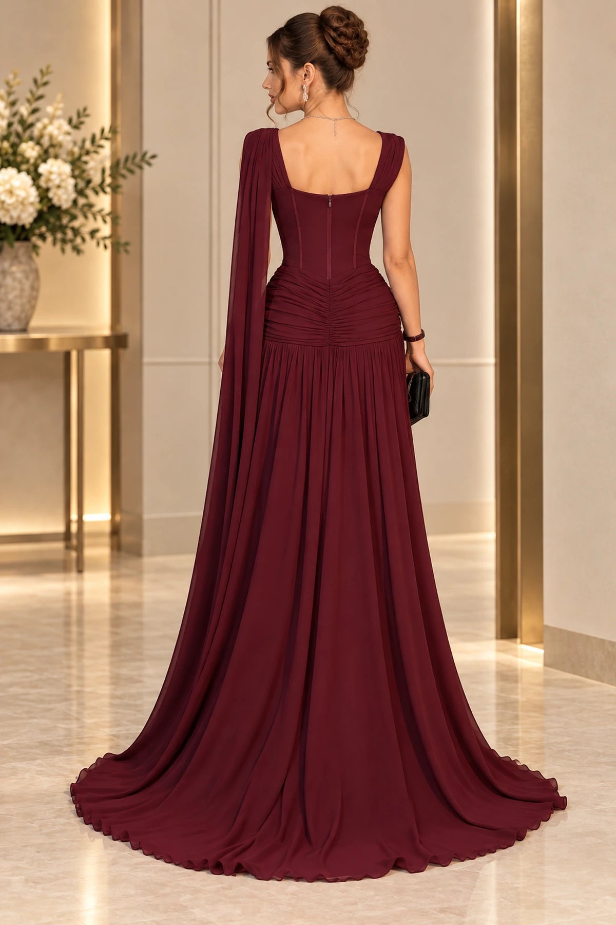 Back view of Graceprom burgundy chiffon prom dress with a low square back, center zipper, ruched hip detailing and trailing shoulder cape.