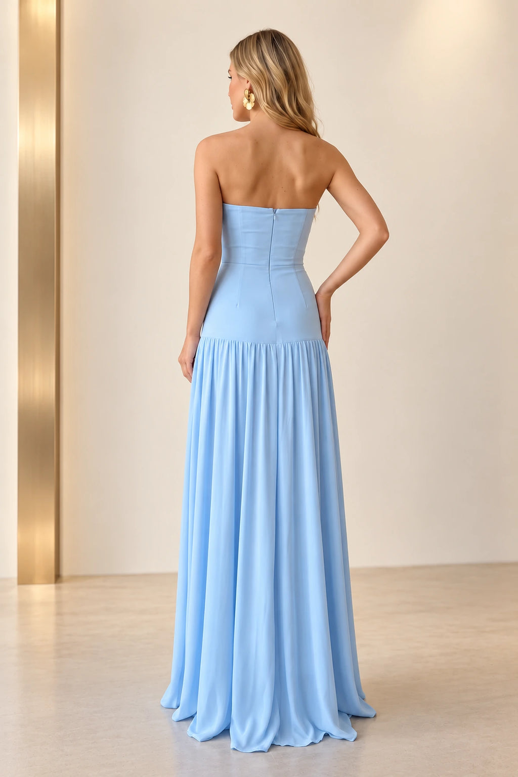 Back view of light blue chiffon prom dress featuring straight strapless back, center zipper, fitted drop waist and flowing gathered floor length skirt