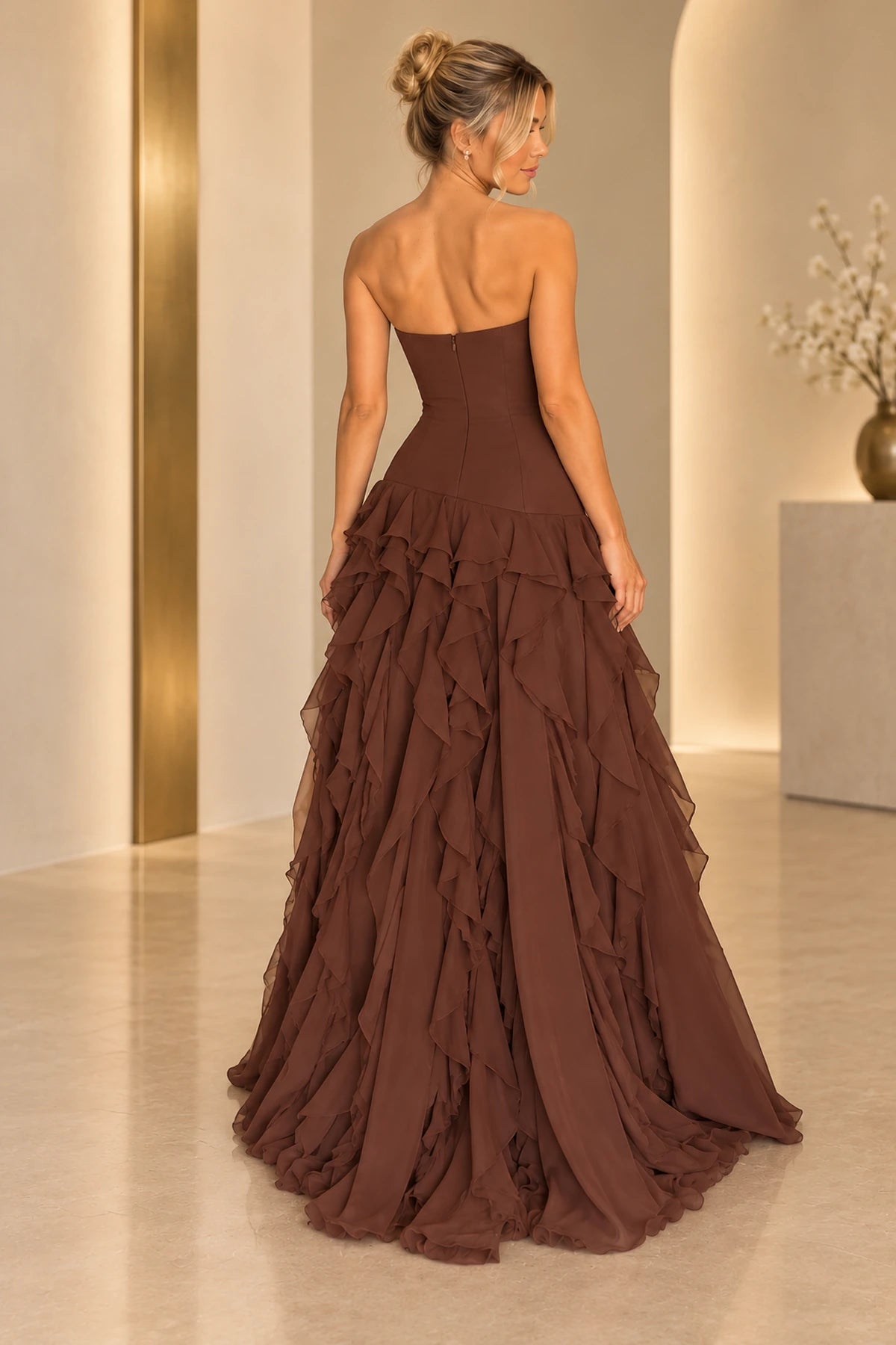 Back view of chocolate brown chiffon prom dress featuring strapless fitted bodice, center zipper, drop waist and cascading layered ruffle skirt