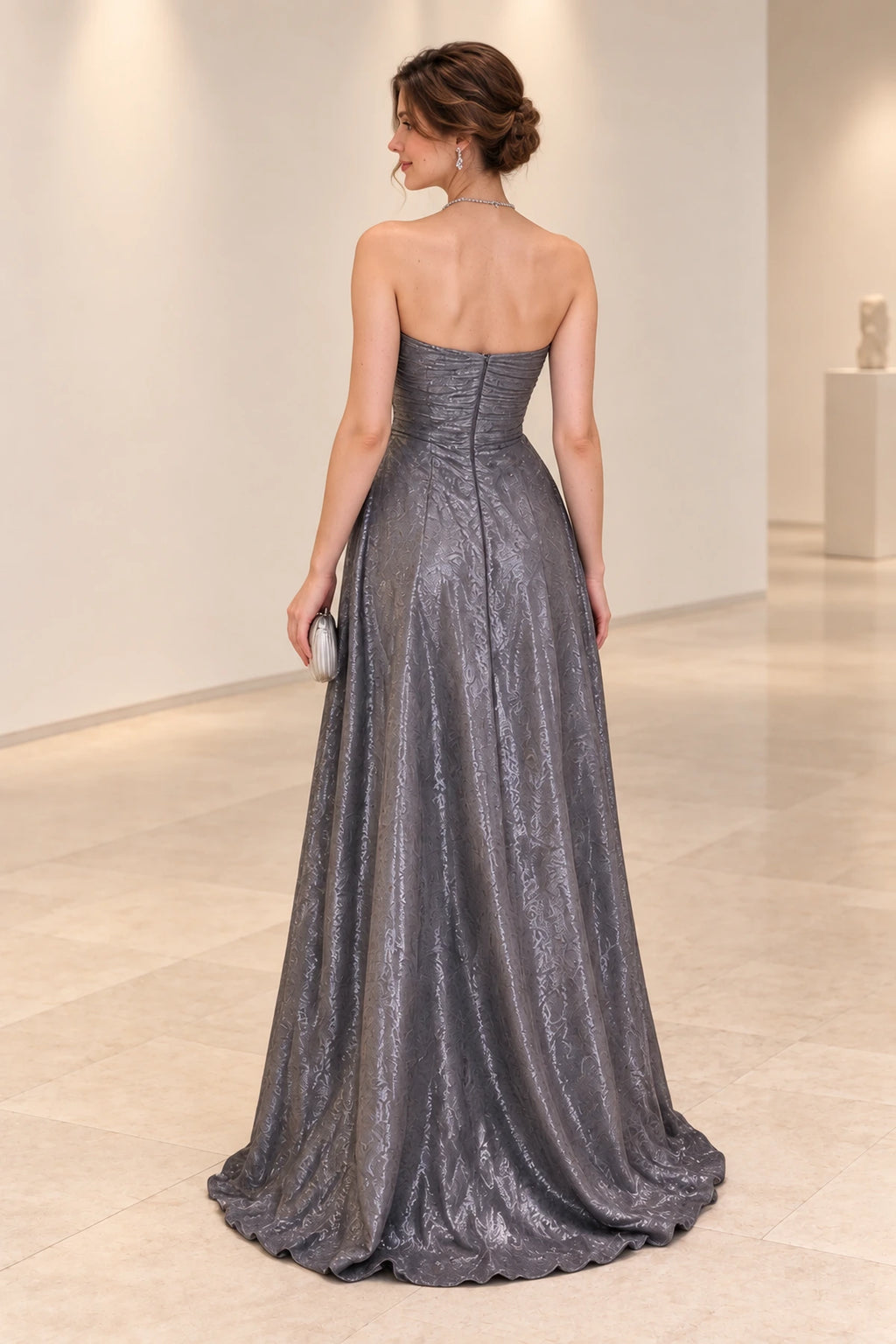 Back view of a silver gray chiffon evening gown with a straight strapless neckline, horizontally ruched bodice, center-back zipper, and flowing A-line skirt.