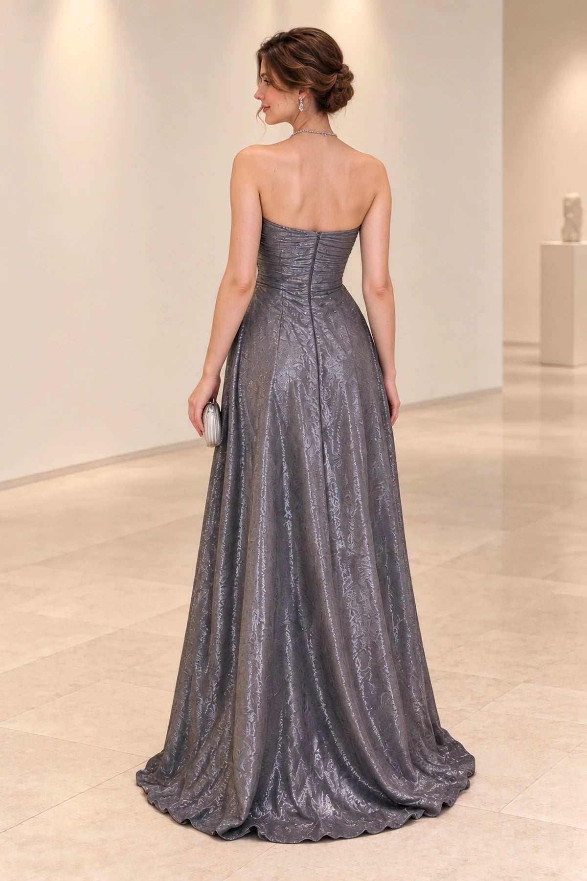 Back view of a silver gray chiffon evening gown with a straight strapless neckline, horizontally ruched bodice, center-back zipper, and flowing A-line skirt.