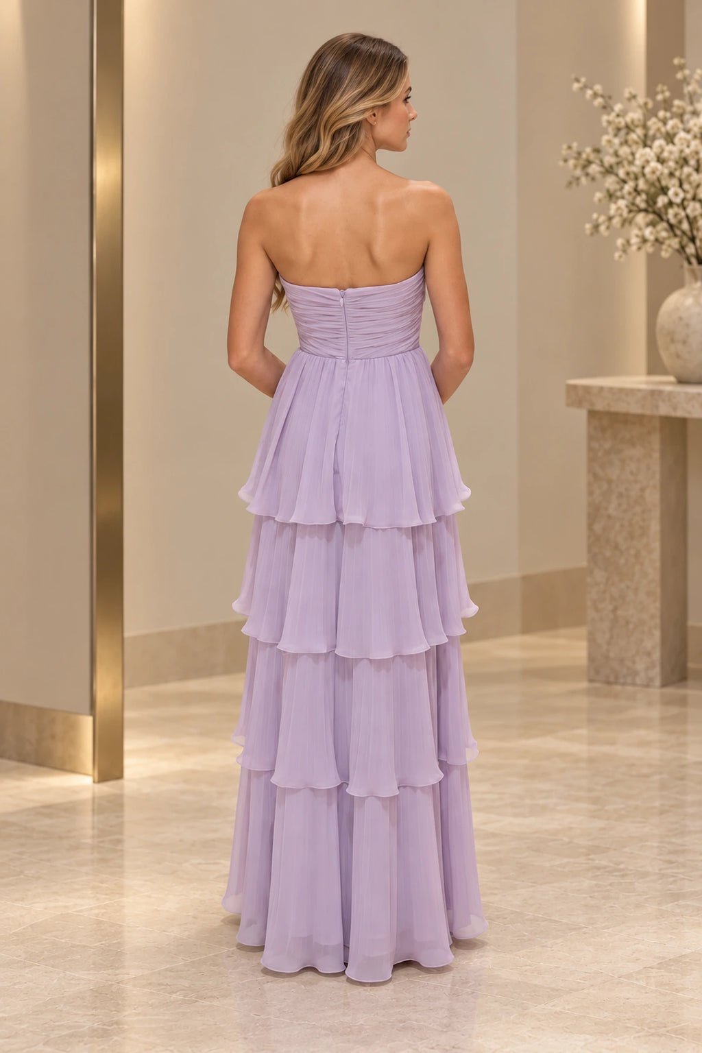 Back view of a lavender Graceprom chiffon prom dress with a low curved neckline, ruched bodice, center zipper and floor-length tiered skirt.