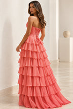Back view of coral pink strapless prom dress featuring a crisscross lace-up corset closure, fitted waist, and cascading tiered ruffle skirt.