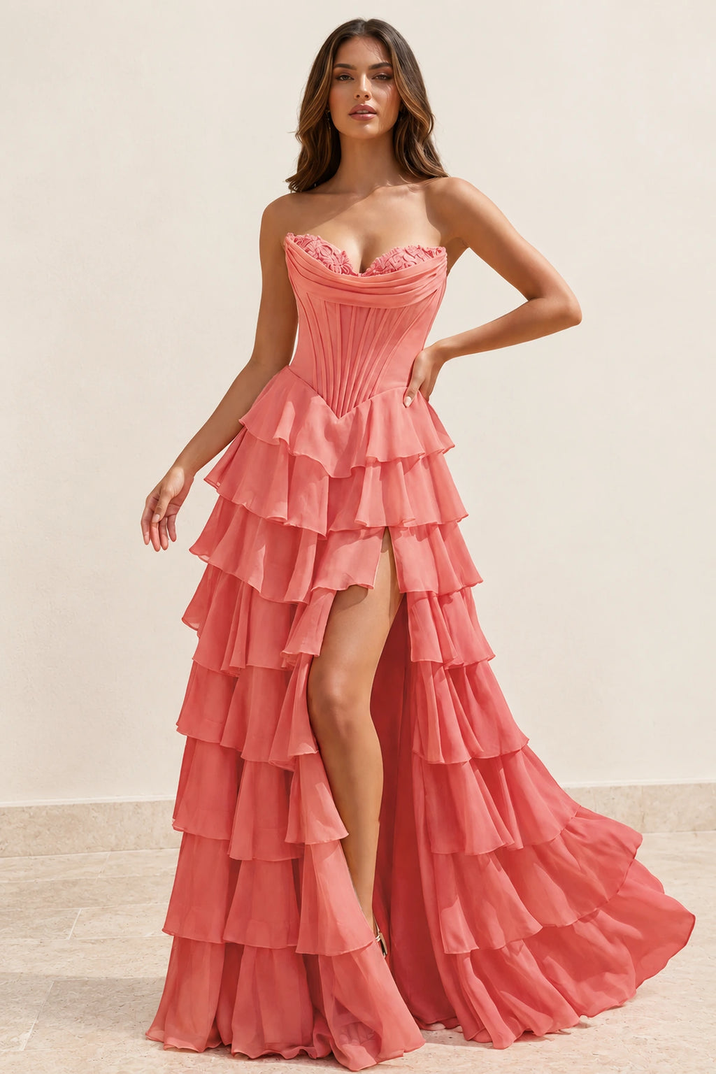 Coral pink A-line prom dress featuring a strapless sweetheart corset bodice, tiered chiffon-look ruffles, front slit, and floor-length skirt by Graceprom.