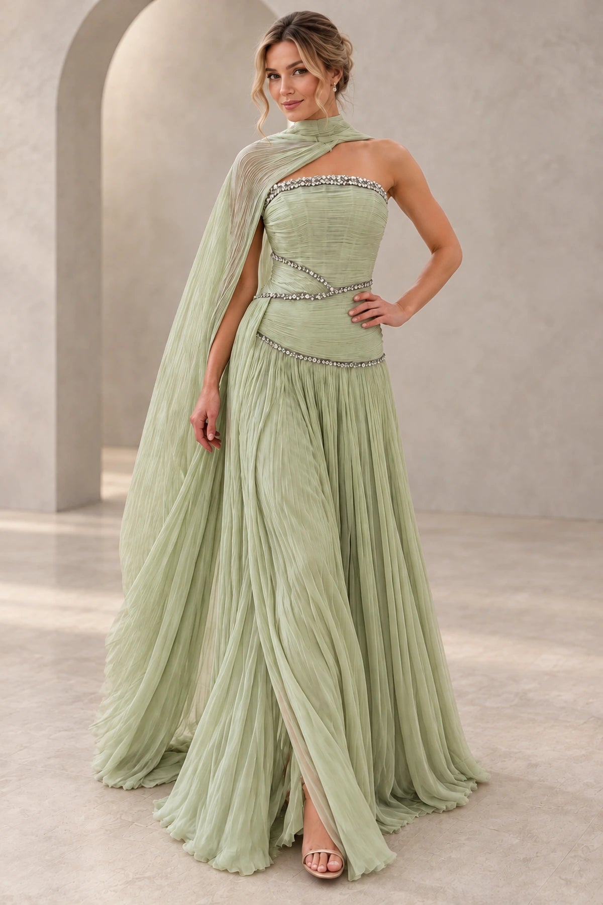 Elegant sage green chiffon prom dress featuring a strapless beaded bodice, asymmetrical cape draping, sparkling waist details and flowing A-line skirt