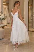 White embroidered lace A-line wedding guest dress with plunging V neckline, lace straps, floral embroidery and scalloped tea length skirt by Graceprom