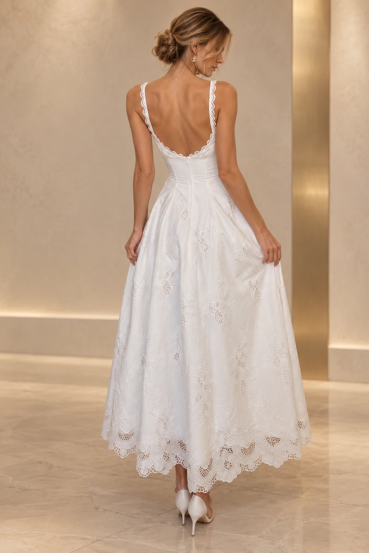 Back view of white embroidered lace wedding guest dress featuring low V back, lace trimmed straps, fitted waist and scalloped tea length A-line skirt