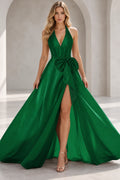 Emerald green A line prom dress with a plunging halter neckline, sparkling bodice, oversized waist bow, and high front slit.
