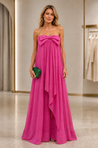 Fuchsia strapless A-line wedding guest dress with oversized bow detail and flowing floor-length skirt