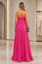Back view of fuchsia wedding guest dress with strapless zipper back and flowing floor-length A-line skirt