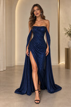 Navy blue sequin mermaid prom dress front view featuring a strapless neckline, ruched fitted bodice, high slit and dramatic flowing chiffon cape sleeves