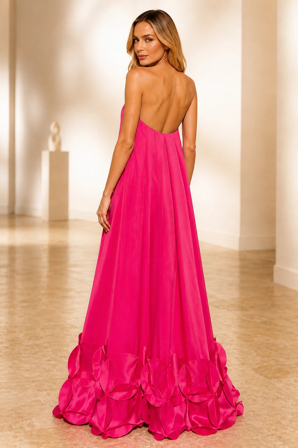 Back view of hot pink evening dress with open back, strapless design and floor-length floral hem skirt