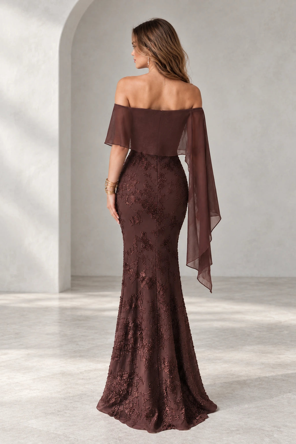 Back view of Graceprom brown lace and chiffon prom dress with a low zipper back, sheer cape overlay and floral detailing along the fitted skirt.