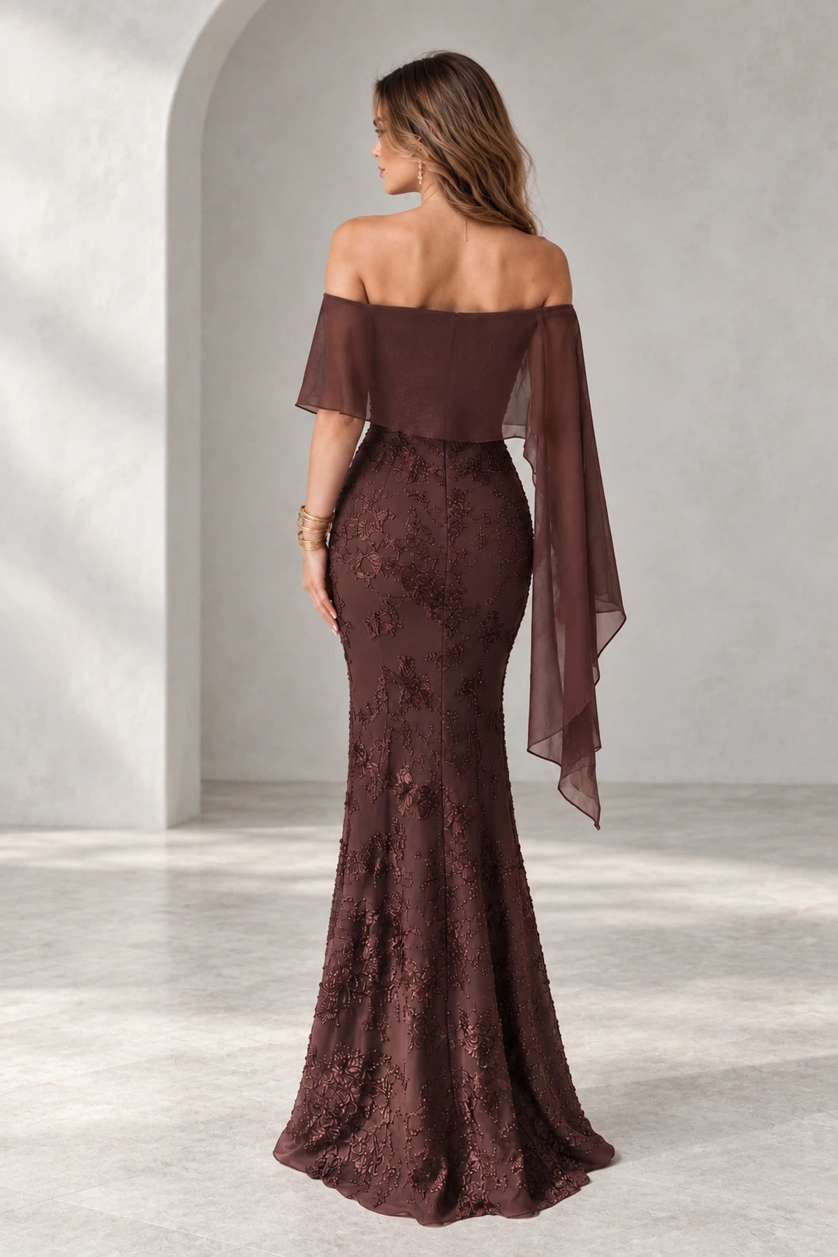 Back view of Graceprom brown lace and chiffon prom dress with a low zipper back, sheer cape overlay and floral detailing along the fitted skirt.