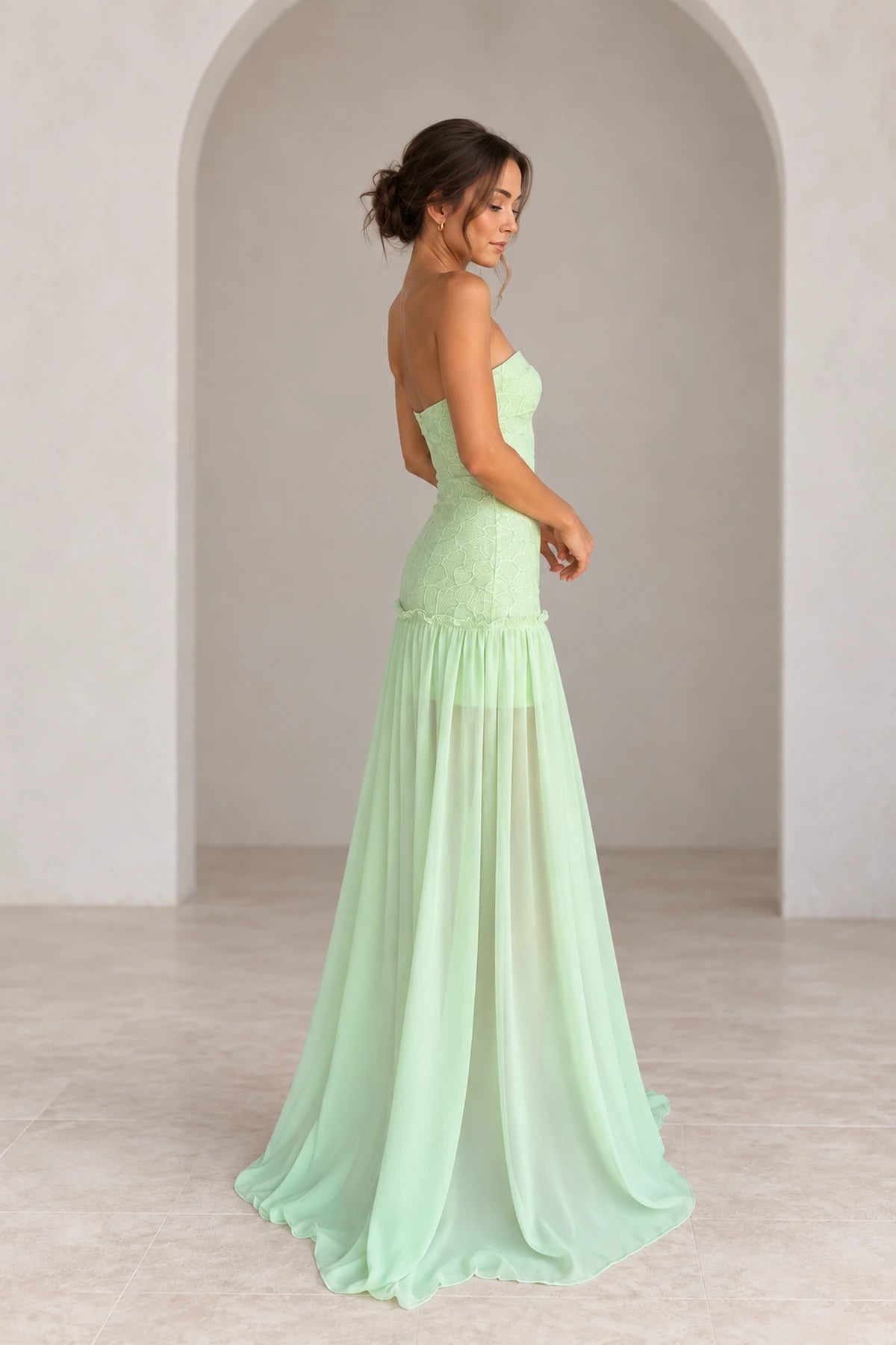 Side back view of mint green lace chiffon prom dress featuring strapless bodice, floral lace detailing, fitted drop waist and flowing long chiffon skirt