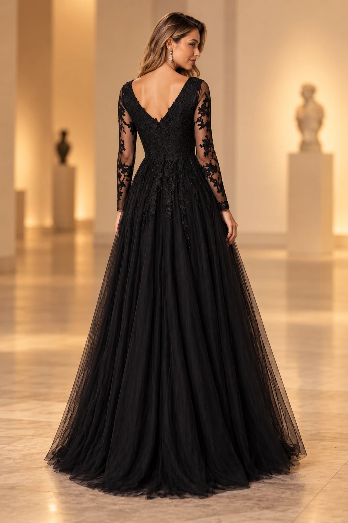 Back view of a black lace prom dress with a V-shaped neckline, center-back zipper, sheer long sleeves, and full tulle skirt.