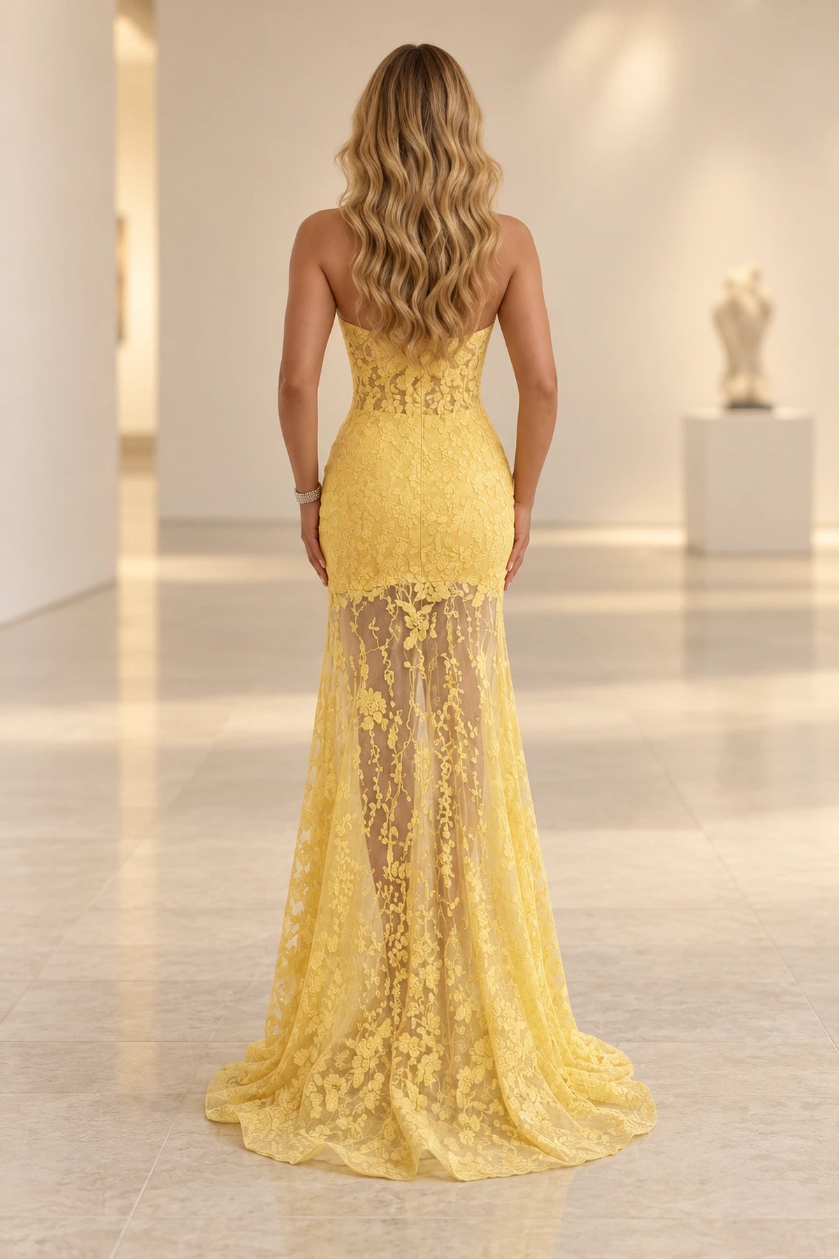 Back view of a yellow Graceprom lace prom dress with a sheer low-back bodice, center zipper, short lining and flowing lace train.